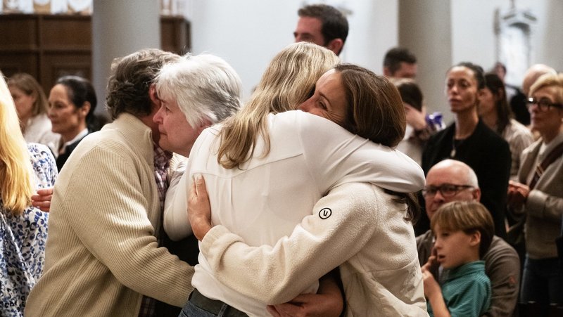 Victims of the Palisades Fire hug during a special Mass for the burned-down Corpus Christi Church at St. Monica in Santa Monica on Jan. 12. (Victor Alemán)