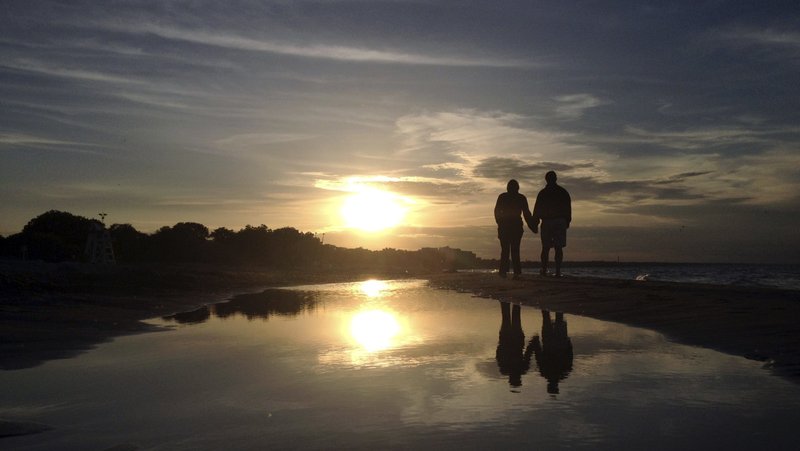 A couple is pictured in a file photo walking along Gillson Beach holding hands as the sun sets in Wilmette, Ill. According to the U.S. Census Bureau, in 2023, 46.4% of American adults -- 117.6 million -- were single. That figure included those who were divorced, widowed or never married. (OSV News photo/Jim Young, Reuters)