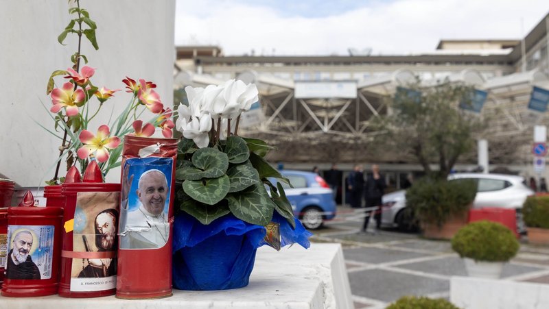 Flowers and votive candles sit at the base of a statue of St. John Paul II outside Rome's Gemelli hospital Feb. 18, 2025, where Pope Francis is a patient. (CNS photo/Pablo Esparza)