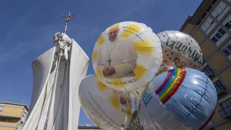 Balloon depicting Pope Francis are seen at the base of a statue of St. John Paul II outside Rome's Gemelli hospital Feb. 23, 2025, where the pope is being treated for double pneumonia. (CNS/Pablo Esparza)