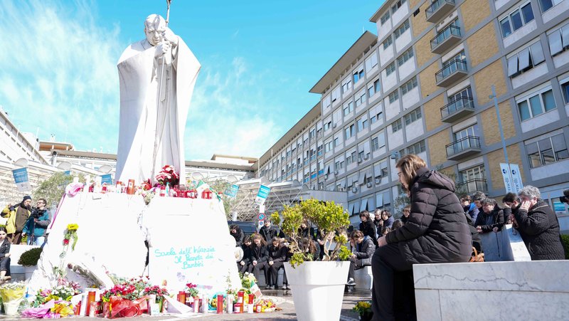 Young people and members of the House of Mary, groups associated with the Pontifical Academy of the Immaculate Conception, and others pray around a statue of St. John Paul II outside Rome’s Gemelli hospital March 2, 2025. Pope Francis is receiving treatment there for double pneumonia. (CNS photo/Lola Gomez)