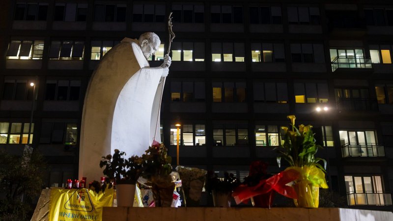 People pray near a statue of St. John Paul II outside Rome's Gemelli hospital where people have left drawings, votive candles, rosaries, flowers, cards for Pope Francis March 8, 2025. (CNS photo/Pablo Esparza)