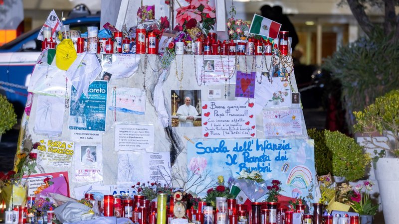 Drawings, votive candles, rosaries, flowers, cards for Pope Francis cover the base of a statue of St. John Paul II outside Rome's Gemelli hospital March 8, 2025. (CNS photo/Pablo Esparza)
