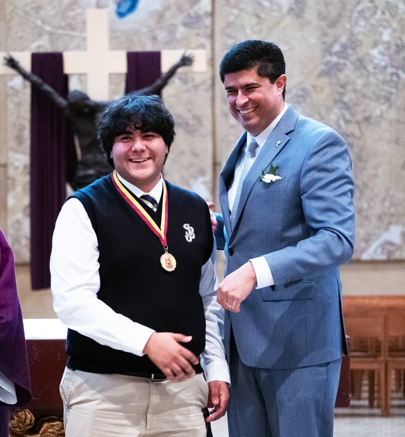 Diego Salcedo of St. John Bosco High School in Bellflower smiles after receiving his medal from Paul Escala, right, superintendent of Catholic schools, at the Christian Service Awards Mass on March 18. (Victor Alemán)