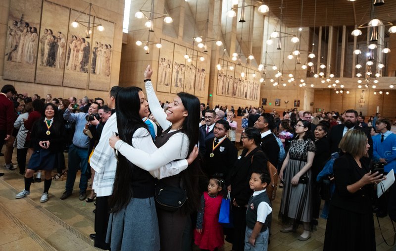 Two young ladies hug following the Christian Service Awards Mass on March 18, where Catholic school students were awarded for more than 36,000 collective hours of Christian service. (Victor Alemán)