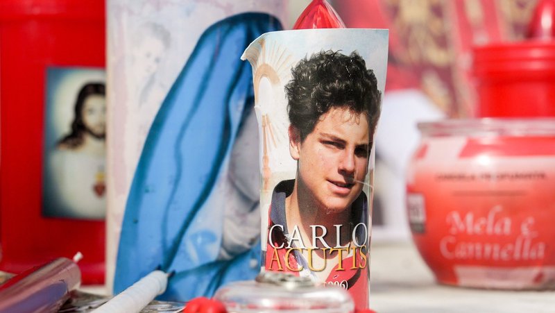 Votive candles and religious images, including one of Blessed Carlo Acutis, are seen at the base of a statue of St. John Paul II outside Rome's Gemelli hospital Feb. 27, 2025, while Pope Francis was being treated there for double pneumonia. (CNS photo/Lola Gomez)