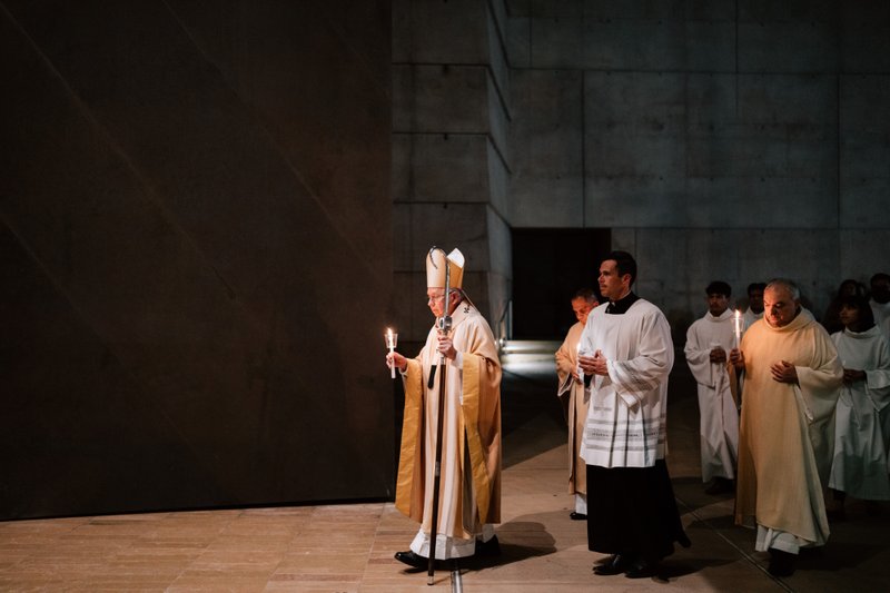 Archbishop José H. Gomez carries a candle while leading the faithful into the Cathedral of Our Lady of the Angels for the Easter Vigil Mass on April 19. (Peter Lobato)