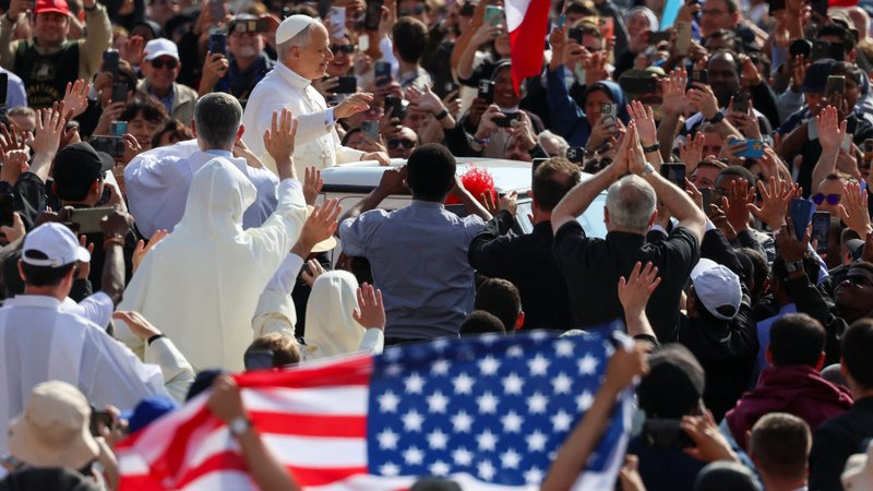 An American flag is displayed as Pope Leo XIV waves as he arrives to celebrate his inauguration Mass at the Vatican May 18. He is the first American pope in history. (OSV News/Claudia Greco, Reuters)