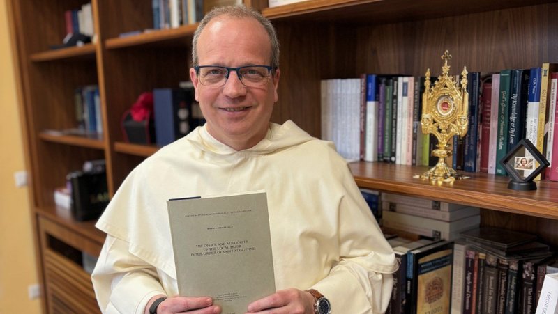 Father Thomas Joseph White, the American rector of the Pontifical University of St. Thomas Aquinas in Rome, is seen May 12, 2025, at the university, also known as the Angelicum. He is holding the doctoral dissertation of the future Pope Leo XIV, which was finalized in 1985 and published two years later. Father White was at St. Peter's Square with hundreds of thousands of people when white smoke rose out May 8 of the chimney atop the Sistine Chapel announcing the election of a new pope. (OSV News photo/courtesy Angelicum)