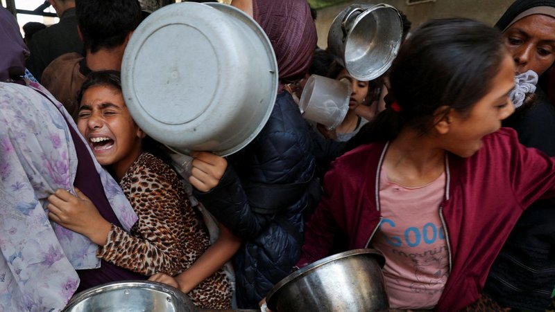 A Palestinian girl displaced by the Israeli military offensive reacts while waiting with other young people May 21, 2025, to receive food cooked by a charity kitchen in Gaza City, Gaza Strip. (OSV News photo/Mahmoud Issa, Reuters)