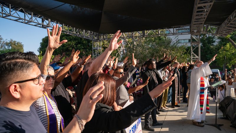 Interfaith leaders and those on stage send out a prayer for peace during an interfaith vigil on June 10 at Grand Park in Los Angeles, during a time of ICE raids and protests. (John Rueda)