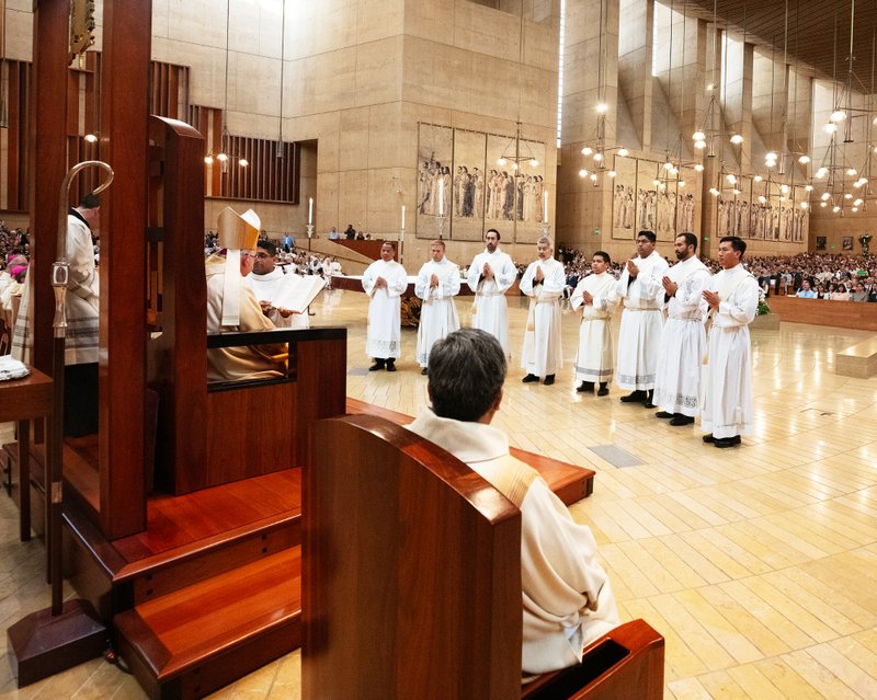 The eight men entering the priesthood stand before Archbishop José H. Gomez during the ordination Mass at the Cathedral of Our Lady of the Angels on May 31. (Victor Alemán)