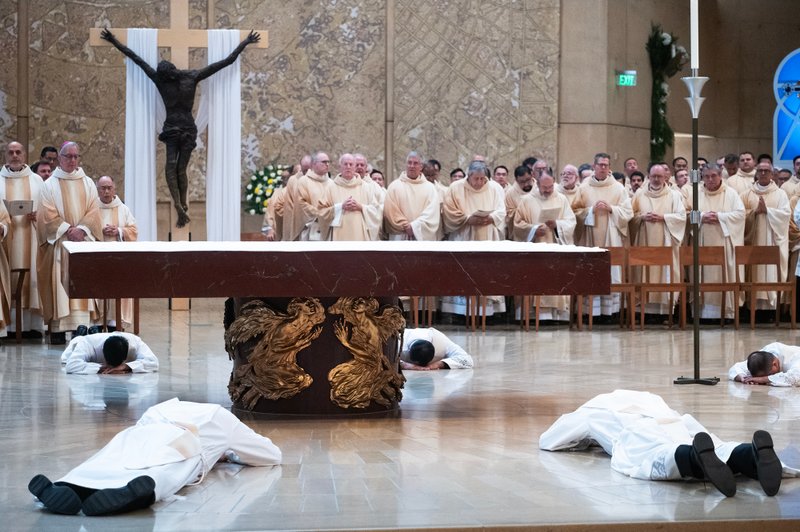 The eight men prostrate themselves at the altar during the ordination Mass at the Cathedral of Our Lady of the Angels on May 31. (Victor Alemán)