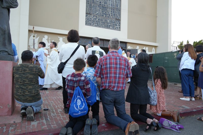 Pilgrims wearing Camino de California backpacks kneel during a Eucharistic procession at Mission San Gabriel Arcángel on June 21 as part of the National Eucharistic Pilgrimage. (Katie Trejo)