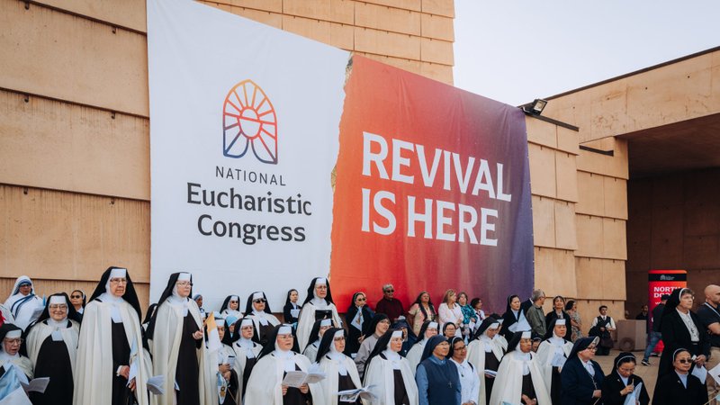 Attendees of the Corpus Christi Mass at the Cathedral of Our Lady of the Angels on June 22 stand in the outdoor plaza under a banner for the National Eucharistic Revival. (Isabel Cacho)
