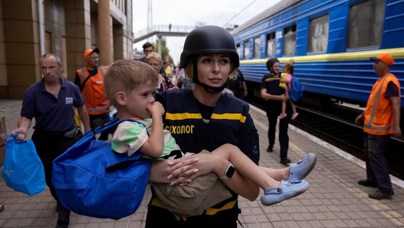 An emergency service worker carries a child as local residents flee via an evacuation train in Pokrovsk, Ukraine, Aug. 22, 2024, as Russian troops advance amid Russia's attack on Ukraine,(OSV News photo/Thomas Peter, Reuters)