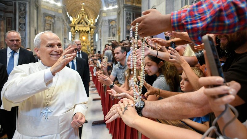 Pope Leo XIV blesses rosaries and greets pilgrims inside St. Peter’s Basilica at the Vatican Aug. 20, 2025, after his weekly general audience. The pope visited them at the conclusion of the audience to offer his blessing, as the Paul VI hall had reached full capacity. (CNS photo/Vatican Media)