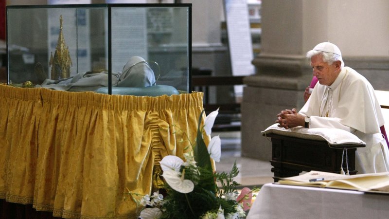 Pope Benedict XVI prays near the mummified body of St. Rose of Viterbo, Italy, in the shrine named after her in Viterbo Sept. 6, 2009. Every year on the Sept. 4 feast of the saint, members of the fraternity "Bearers of St. Rose" carry a 98-foot-tall tower weighing 11,000 pounds through the streets of Viterbo. On Sept. 3, 2025, Italian police foiled an attempted attack on the Catholic festival. (CNS photo/Pier Paolo Cito, pool via Reuters)