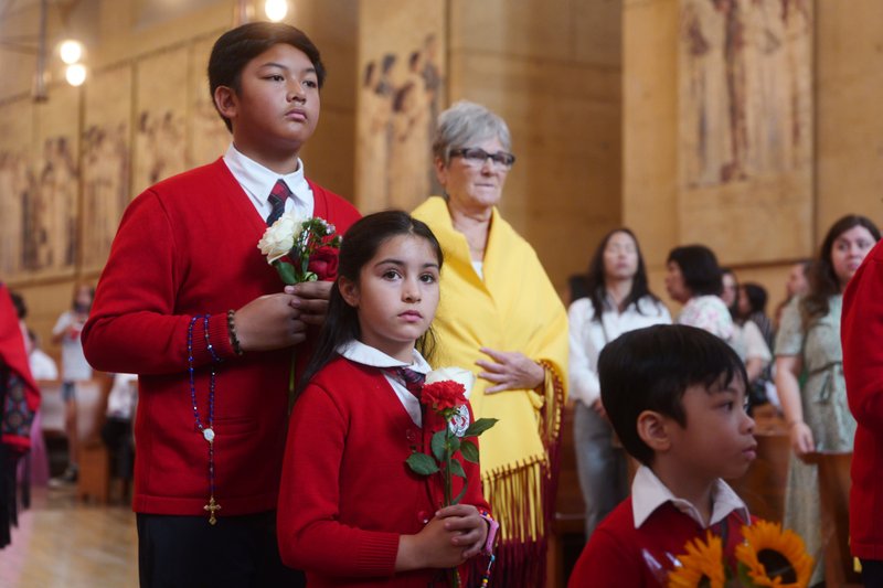 Catholic school students carry flowers to place in front of the Virgin Mary statue during the “One Mother, Many Peoples” Mass at the Cathedral of Our Lady of the Angels on Sept. 6, which celebrated the diverse cultures, organizations, and ethnic ministries in the Archdiocese of Los Angeles. (Reese Cuevas/Archdiocese of Los Angeles)