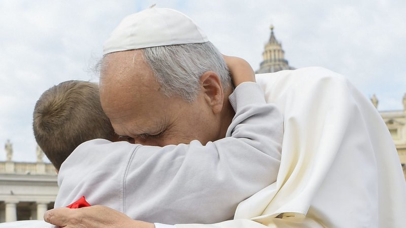 Pope Leo XIV gets a hug as he rides in the popemobile before his weekly general audience in St. Peter's Square at the Vatican Oct. 1, 2025. (CNS photo/Vatican Media)