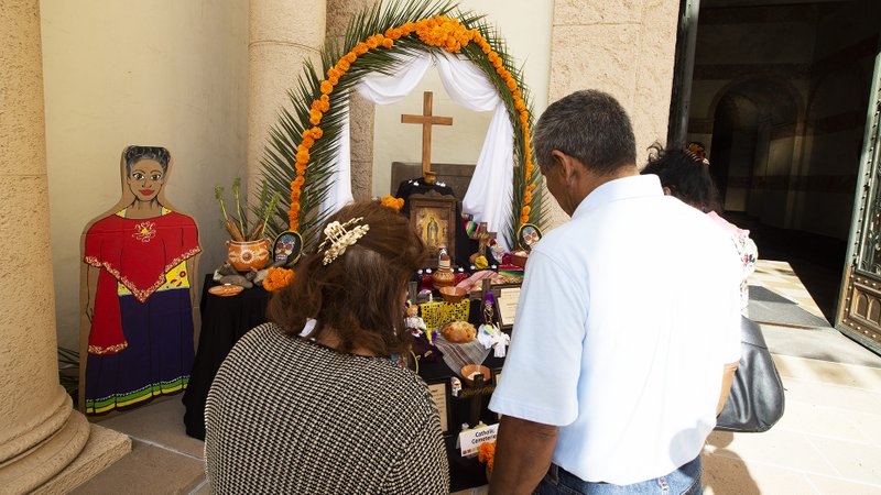 A couple prays before a prayer altar set up for Dia de los Muertos at Calvary Cemetery in East Los Angeles in an undated photo. (Victor Alemán)