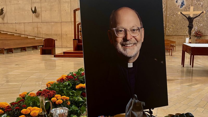 A table displaying personal items belonging to Father Chris Ponnet, including his walking sandals, was set up alongside his portrait at his Nov. 4 funeral at the Cathedral of Our Lady of the Angels. (Tom Hoffarth)