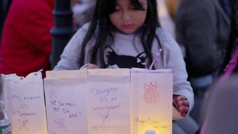 Eight-year-old Zuanny arranges luminaries with messages about her mother, a DACA "Dreamer," herself and her sisters during a vigil at La Colaborativa in Chelsea, Mass., Oct. 10, 2025, for the community affected by raids and detentions by Immigration and Customs Enforcement. (OSV News/Brian Snyder, Reuters)