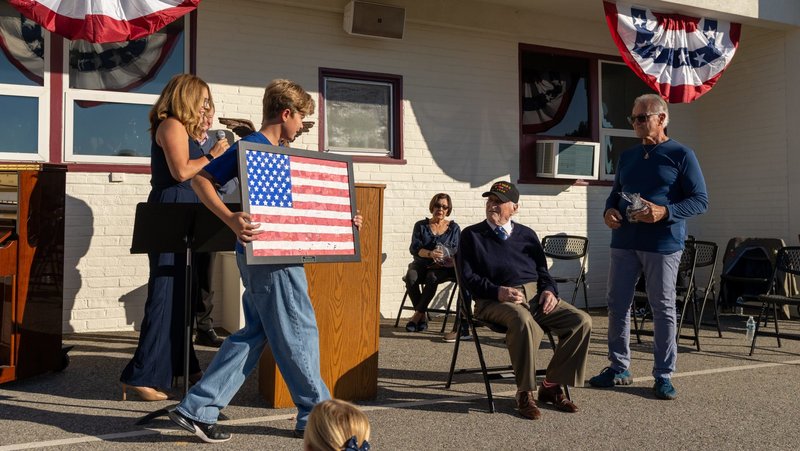 A handmade American flag made by Holy Angels students is presented to Joe “Peppy” Sciarra, a 101-year-old World War II veteran, during a Veterans Day event at the Arcadia school on Nov. 10. (Lawrence Lane)