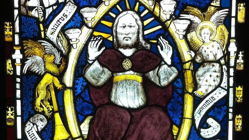 Detail from “St. John Glimpses God in Majesty.” Stained glass from the East Window of York minster. St. John looks through a kind of trapdoor at the bottom left. God, in the center, has summoned him to heaven to show him eternity. Written on the scrolls are words of eternal praise offered to God by the four creatures. (Wikimedia Commons)