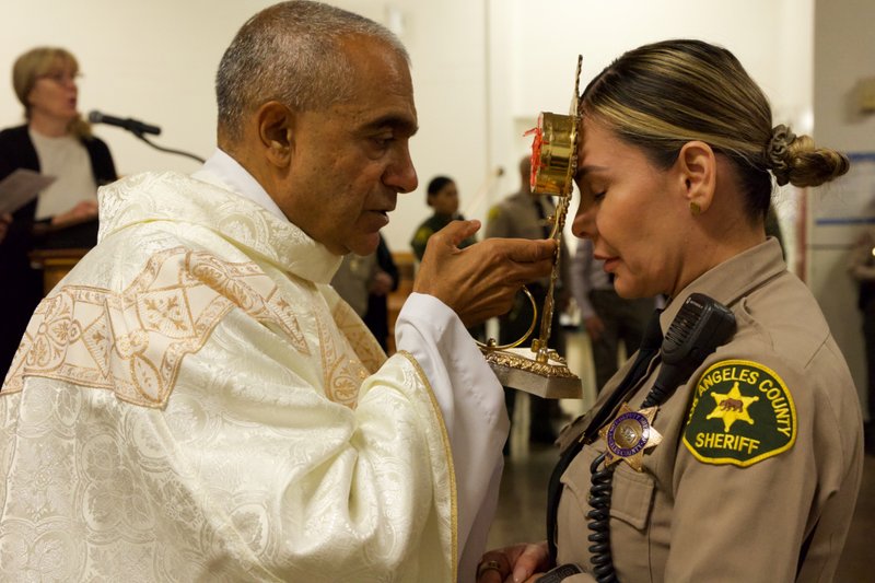 Msgr. Anthony Figueiredo holds the reliquary with St. Carlo Acutis’ pericardium to a sheriff's deputy's forehead during the saint's relic visit to LA Men’s Central Jail on Oct. 20. (Reese Cuevas)