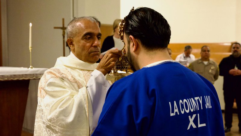 Msgr. Anthony Figueiredo blesses an inmate by holding the reliquary with St. Carlo Acutis’ pericardium to his forehead during the saint's relic visit to LA Men’s Central Jail on Oct. 20. (Reese Cuevas)