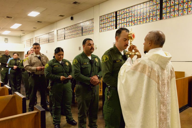 Msgr. Anthony Figueiredo holds the reliquary with St. Carlo Acutis’ pericardium to a sheriff's deputy's forehead during the saint's relic visit to LA Men’s Central Jail on Oct. 20. (Reese Cuevas)
