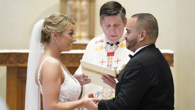 Christina MacDougall places a wedding band on Julio Prendergas’s finger as Msgr. Francis J. Schneider officiates their wedding Mass Aug. 20, 2021, at St. John the Baptist Church in Wading River, New York. (CNS/Gregory A. Shemitz)