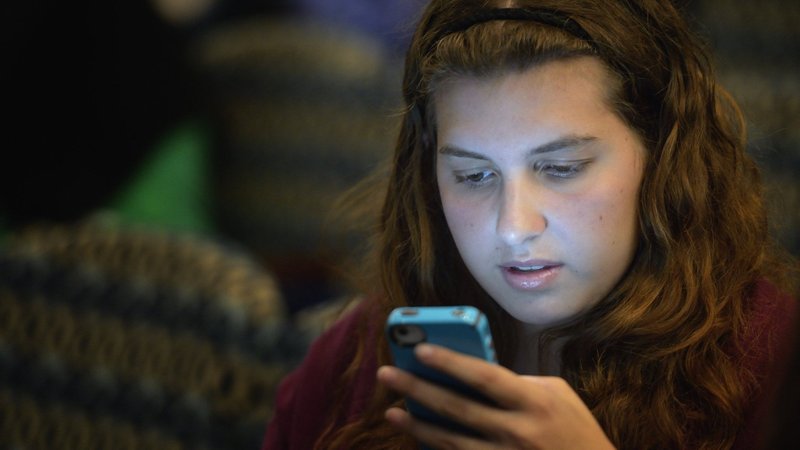 A young woman is pictured in a file photo looking at her cellphone. School smartphone and social media bans are gaining momentum across the U.S. (OSV News photo/Paul Jeffrey)