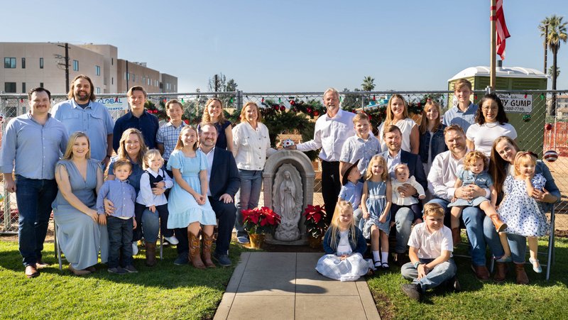 Jackie and Peter Halpin, center, pose with their children, in-laws, and grandchildren — and their surviving Virgin Mary statue — after their lot and rebuilding Altadena home was blessed on Dec. 13, 2025. (Submitted photo)