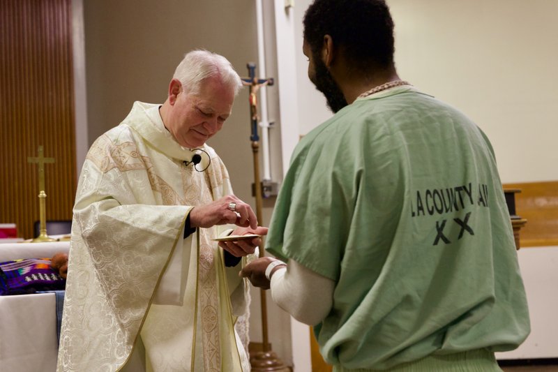 Auxiliary Bishop Matt Elshoff offers Communion during Christmas Day Mass with inmates at Men’s Central Jail near downtown LA. (Reese Cuevas)