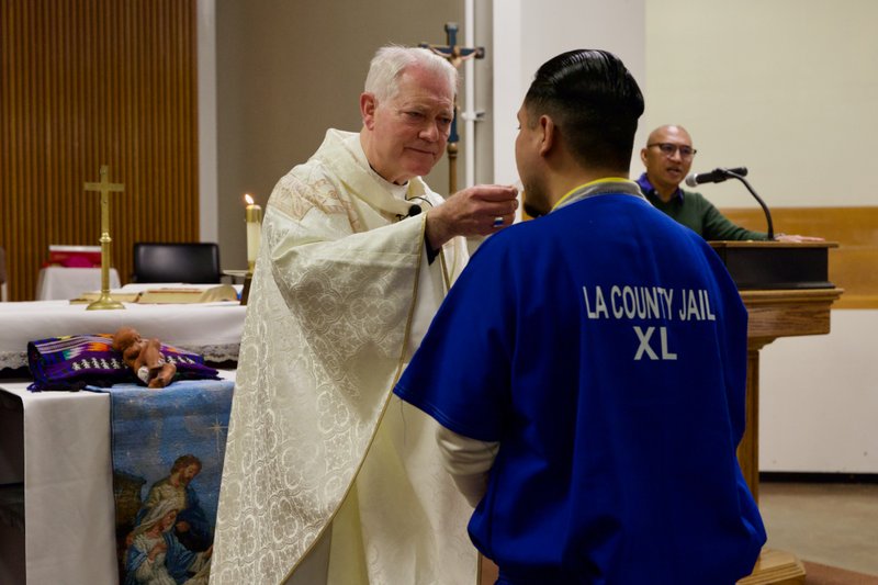 Auxiliary Bishop Matt Elshoff offers Communion during Christmas Day Mass with inmates at Men’s Central Jail near downtown LA. (Reese Cuevas)