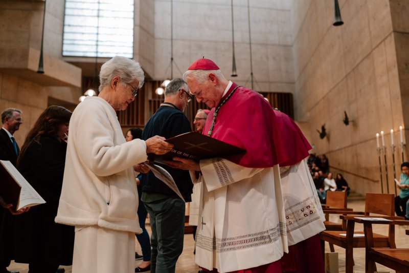 Auxiliary Bishop Matthew Elshoff signs a parish’s Book of the Elect during the Rite of Election ceremony at the Cathedral of Our Lady of the Angels on Feb. 15. (Peter Lobato)