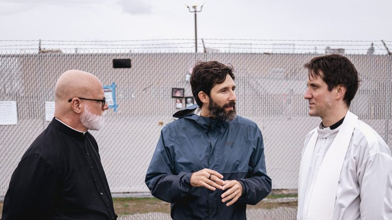 Michael Okinczyc-Cruz, executive director of the Coalition for Spiritual and Public Leadership, talks to Claretian Father Paul Keller, left, and Jesuit Father David Inczauskis after the two priests completed a Holy Thursday visit to the Broadview ICE processing facility in Illinois to minister to 14 people without proper authorization to be in the U.S. (OSV News photo/courtesy of Coalition for Spiritual and Public Leadership)