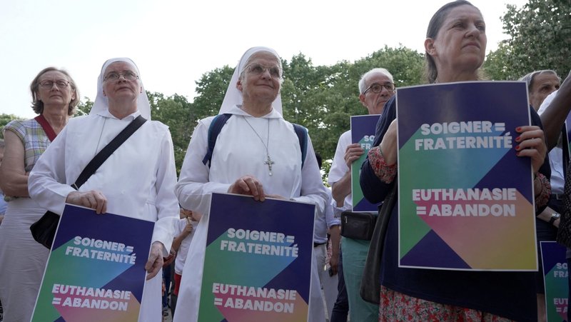 Opponents of "assisted dying" gather during a vote by members of parliament on a bill establishing the right to medical aid in dying at the National Assembly in Paris July 15, 2026. The placards read "Caring = fraternity – Euthanasia = abandonment. In reaction the same day, the French bishops decried the vote as 'turning point' in nation's history of alleviating suffering and accompanying "each person to the natural end of their life." (OSV News photo/Noemie Olive, Reuters)
