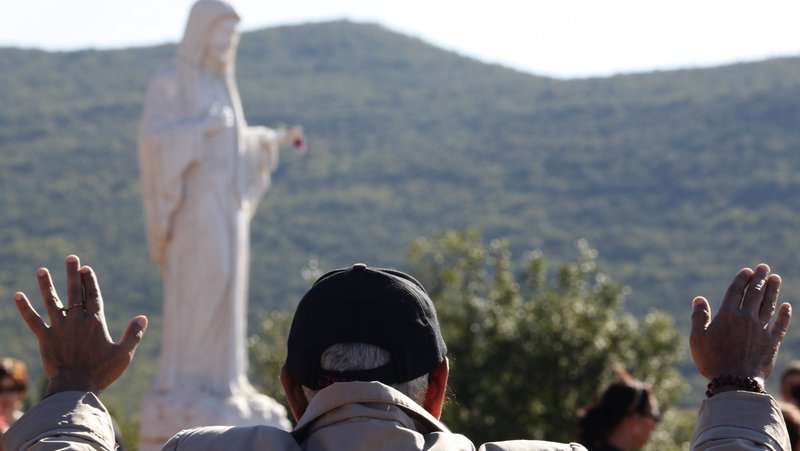 A file photo shows a man praying near a statue of Mary on Apparition Hill in Medjugorje, Bosnia-Herzegovina. Authorities were investigating a string of early-morning vandalism and arson attacks at Medjugorje July 28, 2026. Police said several statues of the Virgin Mary were defaced with black spray paint and blasphemous graffiti. (OSV News photo/Matko Biljak, Reuters)