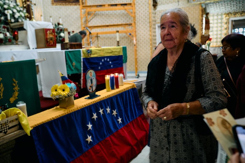 A parishioner passes the Venezuelan flag during a special Mass at Nuestra Señora de Guadalupe Church in East LA on Sunday, June 28, to pray for victims of the Venezuela earthquakes. (John Geronilla)