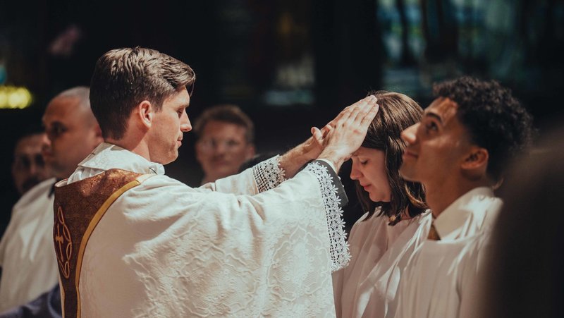 Father Matthew Wheeler, the pastor at Our Savior Parish at USC, blesses those entering into the Catholic Church during the Easter Vigil Mass on April 4. (USC Caruso Catholic Center)