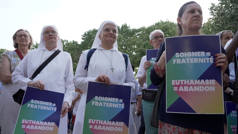 Opponents of "assisted dying" gather during a vote by members of parliament on a bill establishing the right to medical aid in dying at the National Assembly in Paris July 15, 2026. The placards read "Caring = fraternity – Euthanasia = abandonment. In reaction the same day, the French bishops decried the vote as 'turning point' in nation's history of alleviating suffering and accompanying "each person to the natural end of their life." (OSV News photo/Noemie Olive, Reuters)