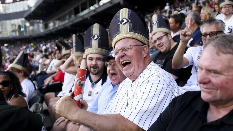 White Sox fans smile while wearing "pope hats" at an Aug. 11, 2026, baseball game at Rate Field in Chicago. The White Sox game paid tribute to Pope Leo XIV, a native of Dolton, Ill., with a first pitch thrown by a nun, a performance by the ChiTown Popes, and a fifth inning "sign of peace" while taking on the Cincinnati Reds. (OSV News photo/courtesy of the Chicago White Sox)