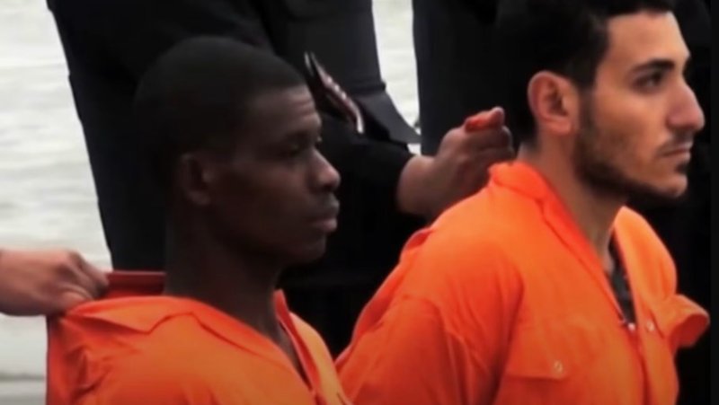 St. Matthew Ayariga, left, and another captive being held by ISIS terrorists on Feb. 15, 2015. “Vaticano”/Screenshot via EWTN)
