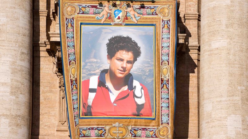 A tapestry depicting St. Carlo Acutis hangs from the facade of St. Peter’s Basilica during the Mass for his canonization at the Vatican Sept. 7, 2025. (CNS photo/Lola Gomez)
