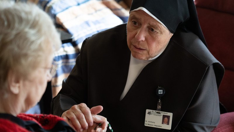 A Carmelite Sister comforts a resident Aug. 21, 2026, at St. Patrick’s Residence in Naperville, Ill. Cardinal Blase J. Cupich of Chicago, the Carmelite Sisters for the Aged and Infirm and the Chicago Province of the Little Sisters of the Poor, and an Illinois pharmacist sued Illinois Sept. 3 over the state's physician-assisted suicide law, which permits physicians to aid terminally ill adults in dying by suicide. (OSV News photo/courtesy Becket)
