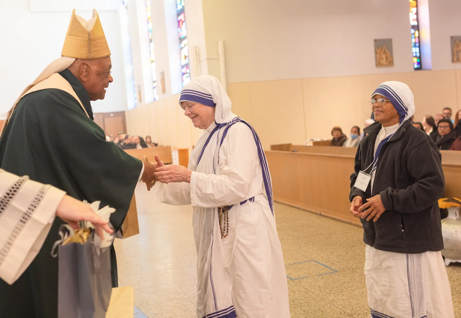 After celebrating a Mass on Feb. 9 at St. Bernard of Clairvaux Church in Riverdale Park, Maryland, to honor men and women in consecrated life serving in The Roman Catholic Archdiocese of Washington who are celebrating milestone anniversaries, Cardinal Wilton Gregory presents a gift to Sister Veronica Irene Neubauer of the Missionaries of Charity who is marking her 40th anniversary in religious life. At right is Sister M. Shanti Shalini Joseph, a contemplative nun with the Missionaries of Charity who is also marking her 40th anniversary. (Catholic Standard photo by Rachel Lincoln)