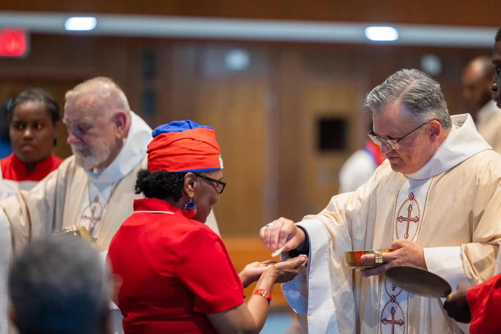 Archbishop Robert G. Casey of Cincinnati gives Communion to a woman at Our Lady of Sorrows Church in Takoma Park, Maryland, on July 28, 2026 during a Mass of Solidarity with the Haitian community and those impacted by changes to immigration policy. At left also distributing Communion at the Mass was Archbishop Thomas G. Wenski of Miami. (Catholic Standard photo by Mihoko Owada)